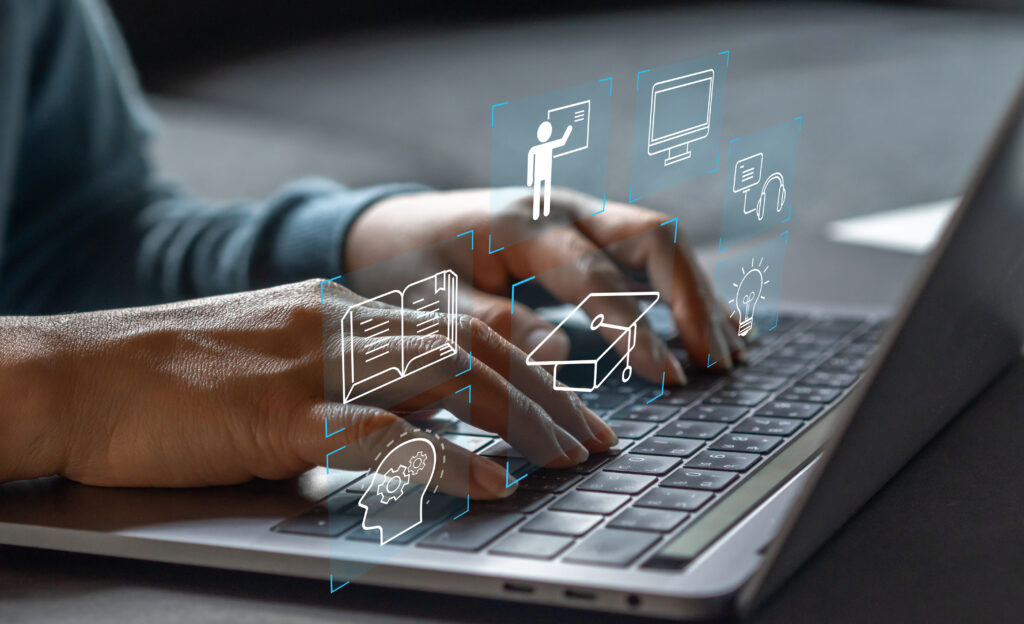 Close-up of hands typing on a laptop keyboard with digital education icons overlayed, including a graduation cap, book, computer, and headset, symbolizing digital classroom solutions, smart technology, and interactive learning.